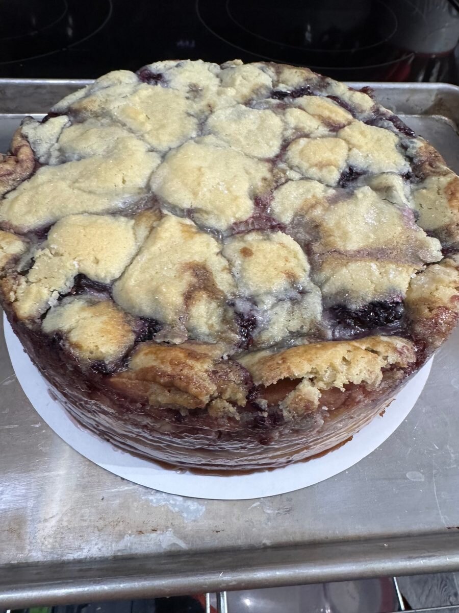 Blackberry cobbler cheesecake topped with golden cobbler crust and blackberries.