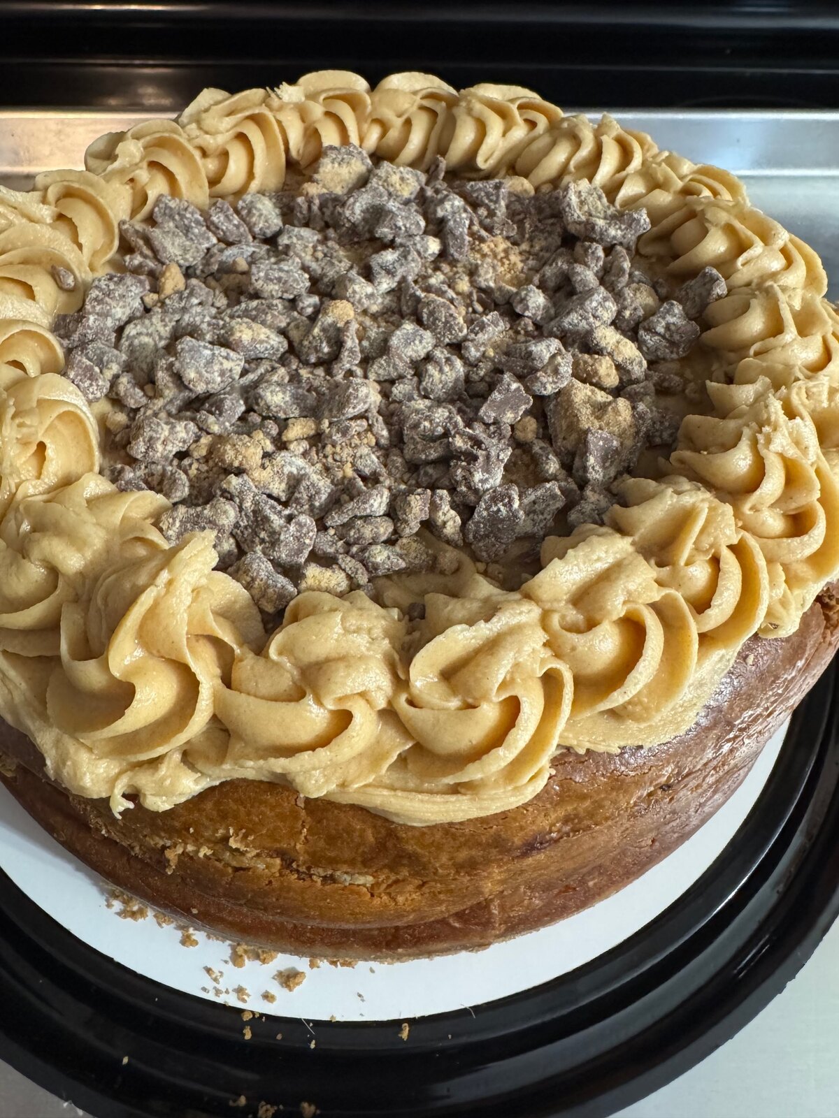 Peanut butter cheesecake topped with crushed Reese's pieces and a ring of peanut butter frosting.